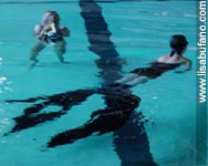 Lisa Bufano is being filmed, swimming in a pool, wearing a large single swimming-fin attached to her legs